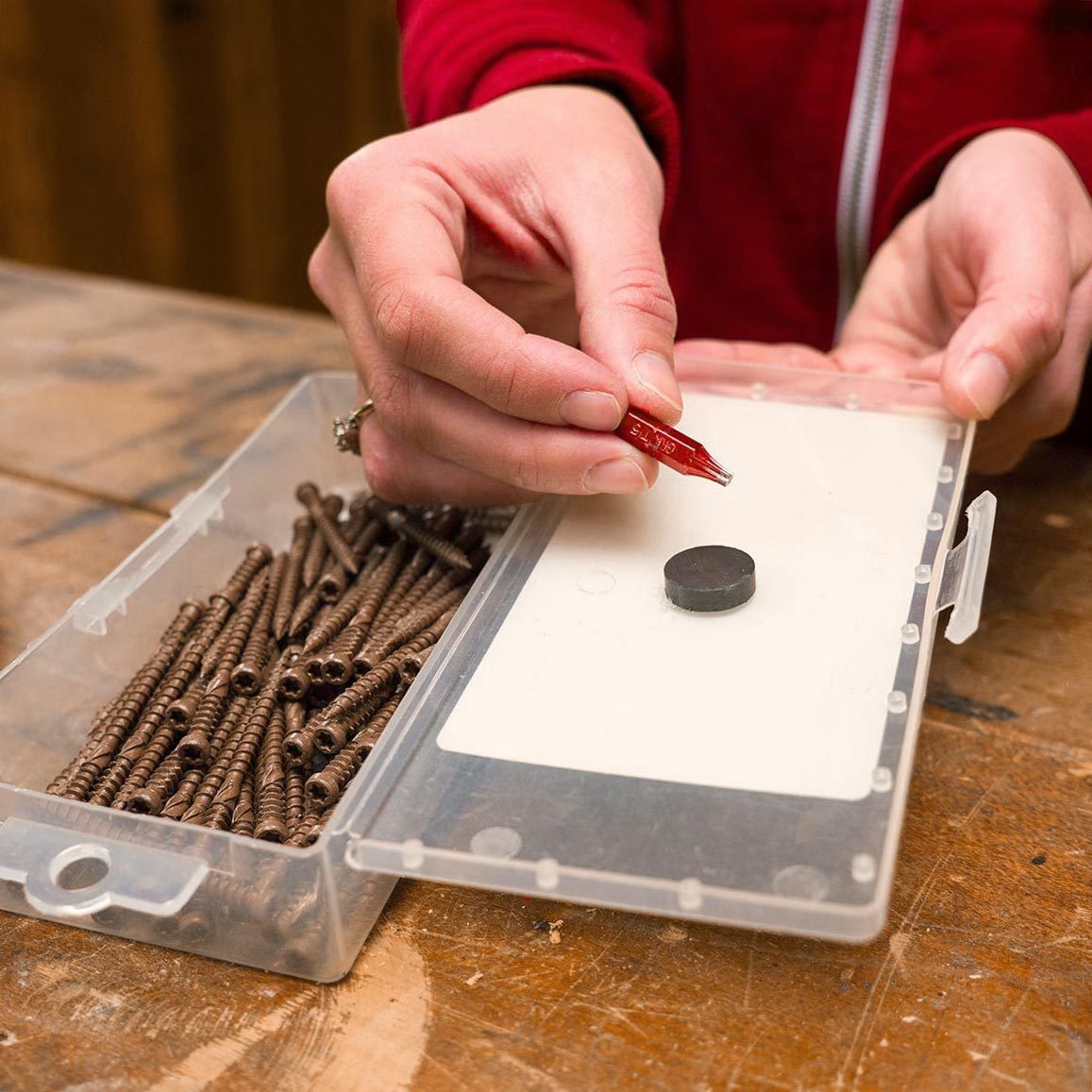 a small plastic container filled with screws and a magnet in the lid