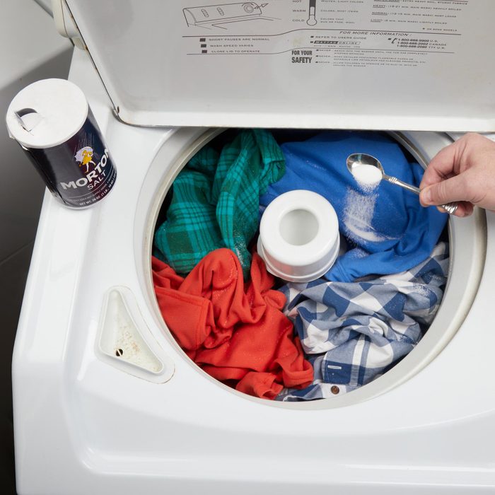 hand putting salt in a full washing machine