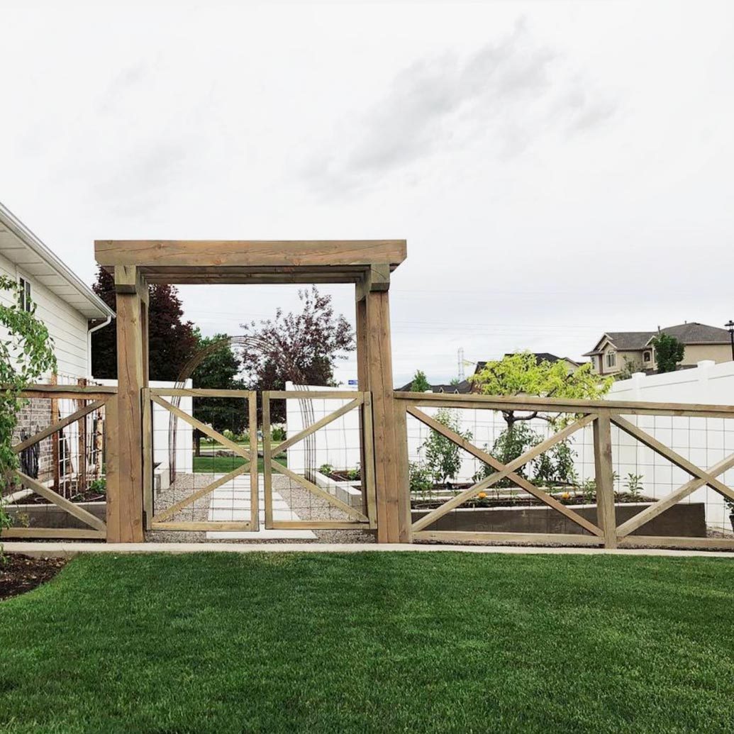 cross buck wooden fence in a residential neighborhood closing a yard with green grass