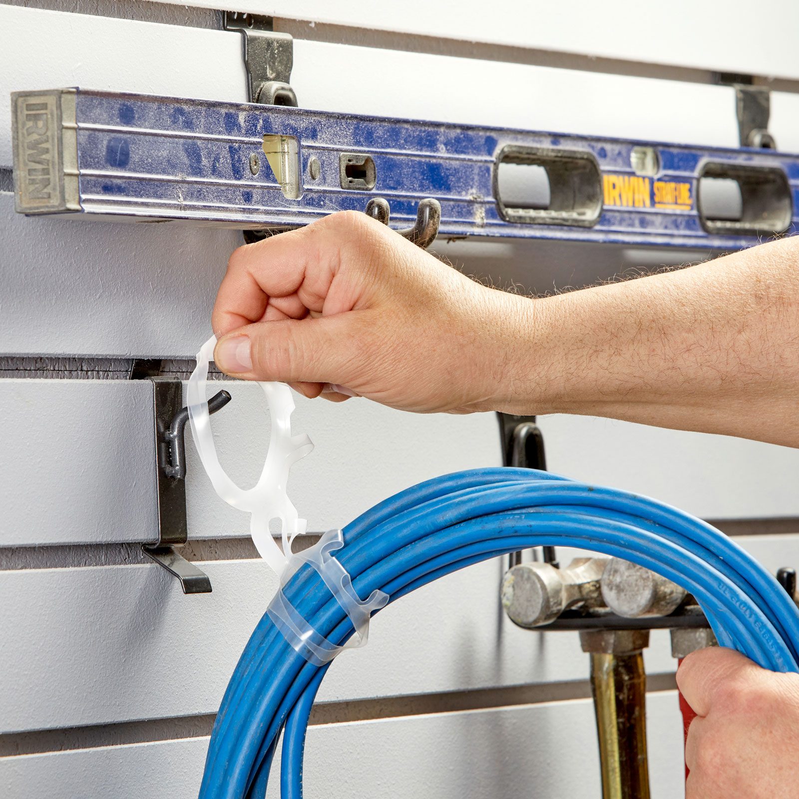 person using a plastic six-pack ring to organize an extension cord