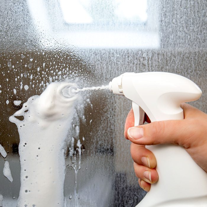 using foaming spray cleaner to remove shower scum from glass shower door