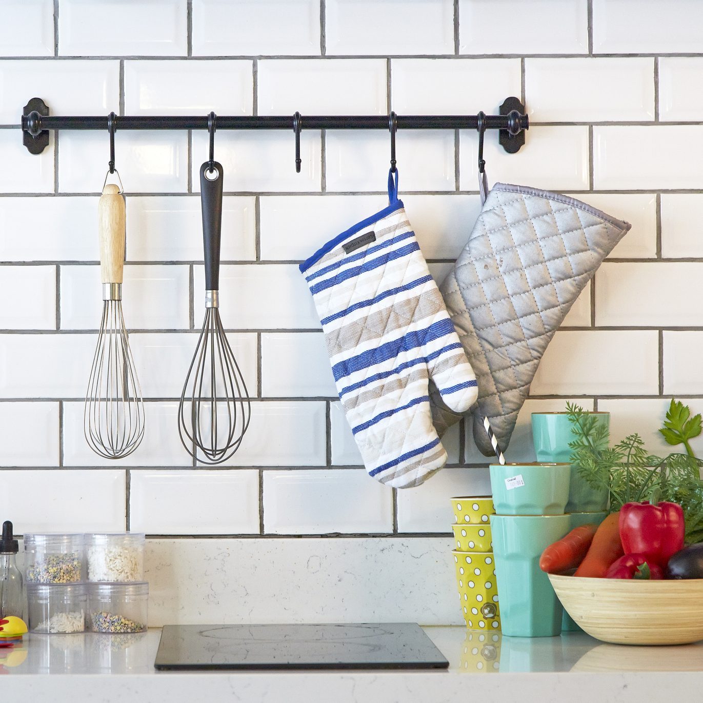 Modern kitchen with utensils and oven mitts hanging from a curtain rod