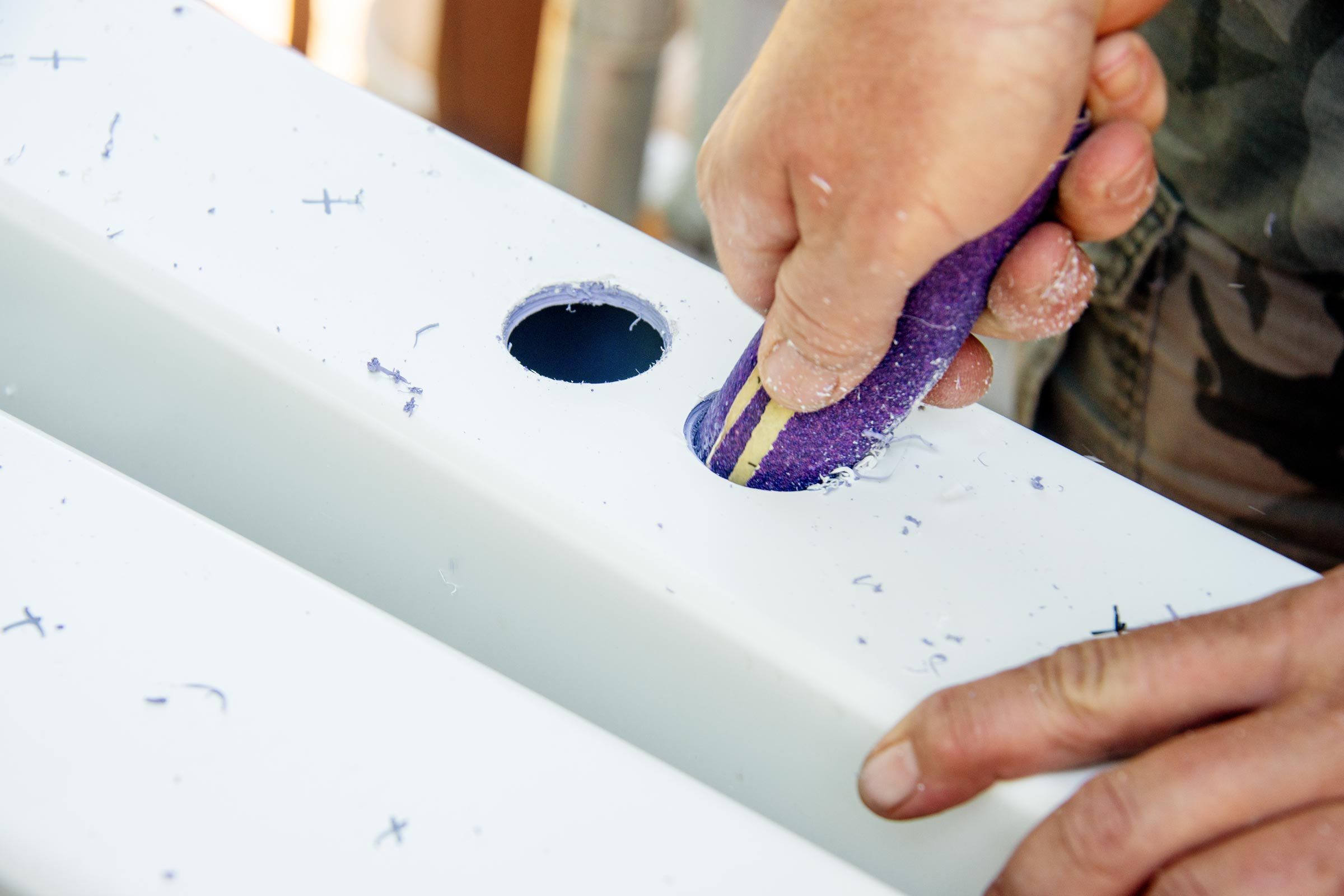 smoothing out the rough edges of the drilled holes with sandpaper