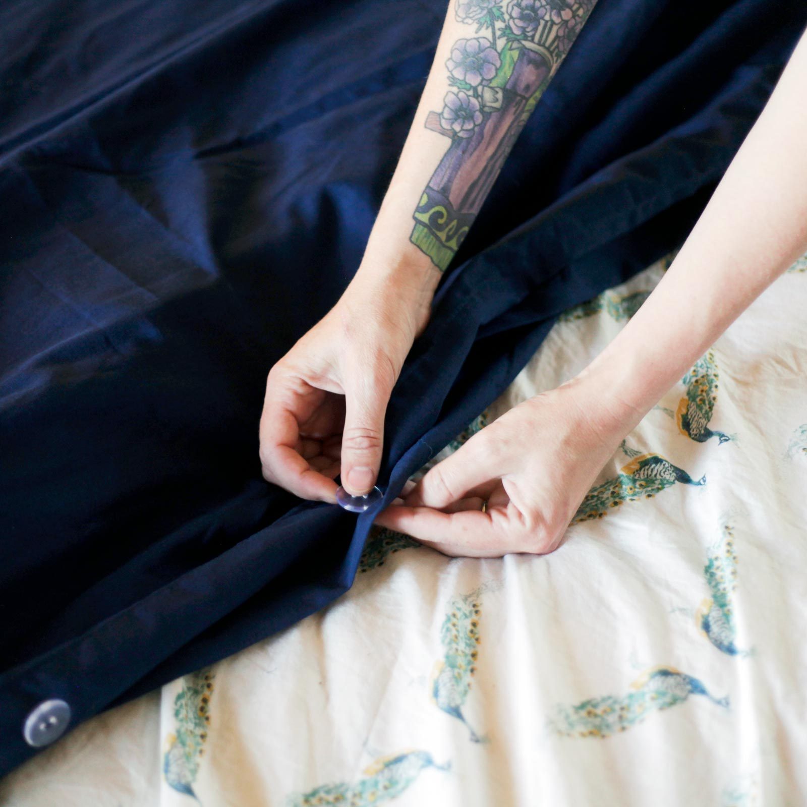 close up of hands buttoning a blue duvet