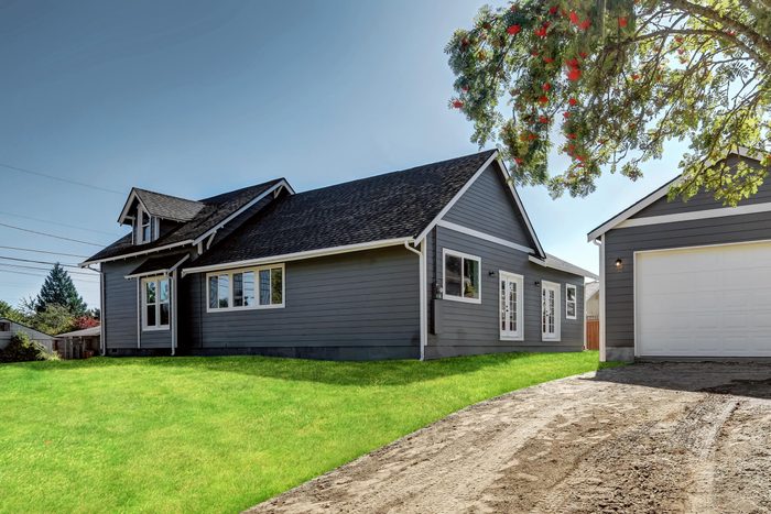 Backyard view of dark grey siding house with detached garage