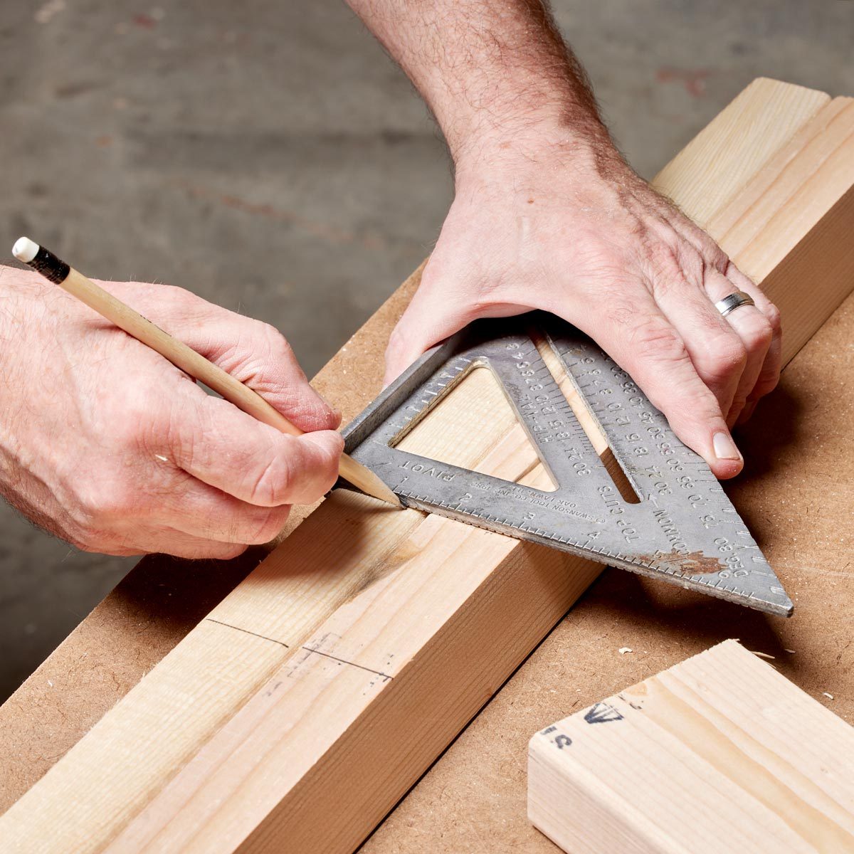 close up of hands marking measurements on a piece of wood with a pencil