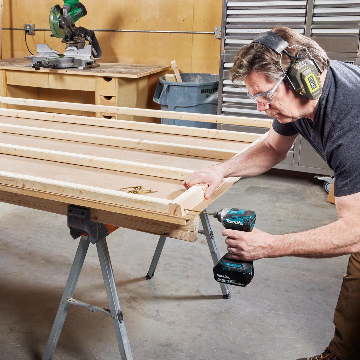 man using a drill to assemble the sauna walls