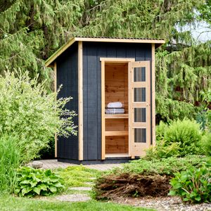 finished sauna outside in a lush backyard with gardens