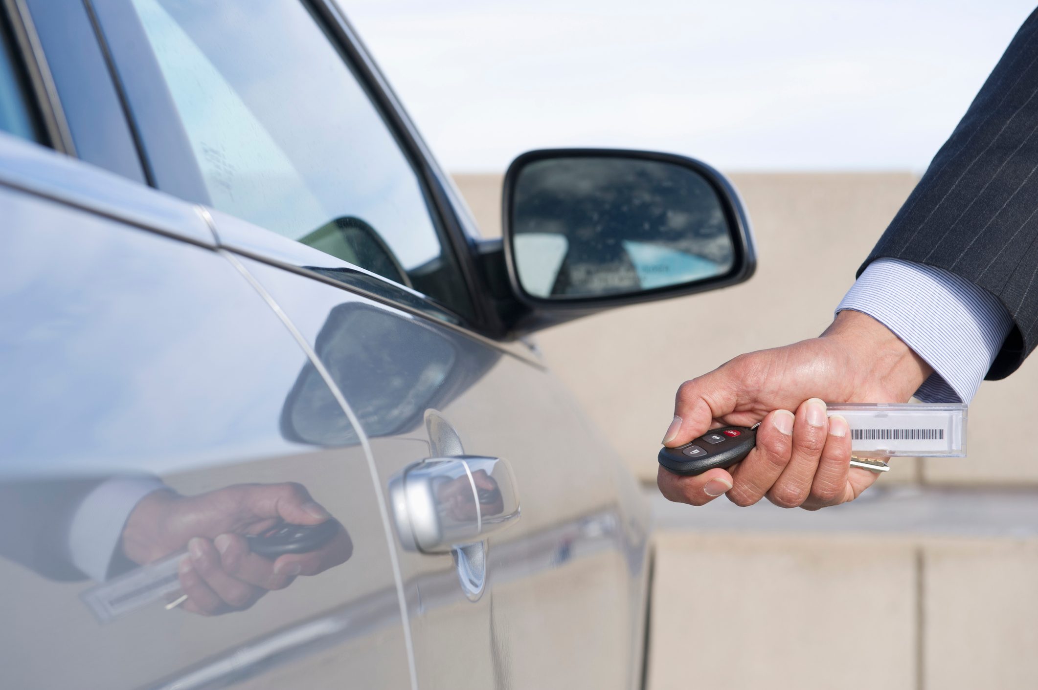 Hispanic businessman using electronic key to open car door