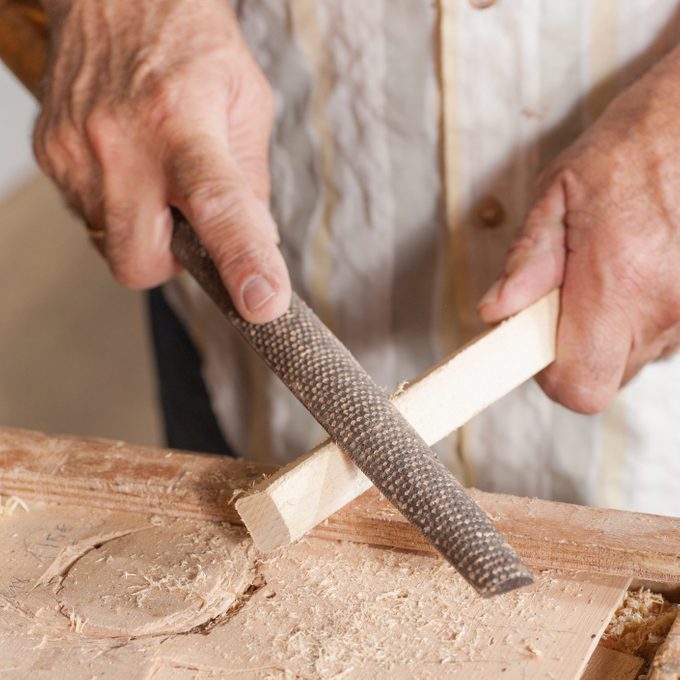 Carpenter working with a traditional rasp tool