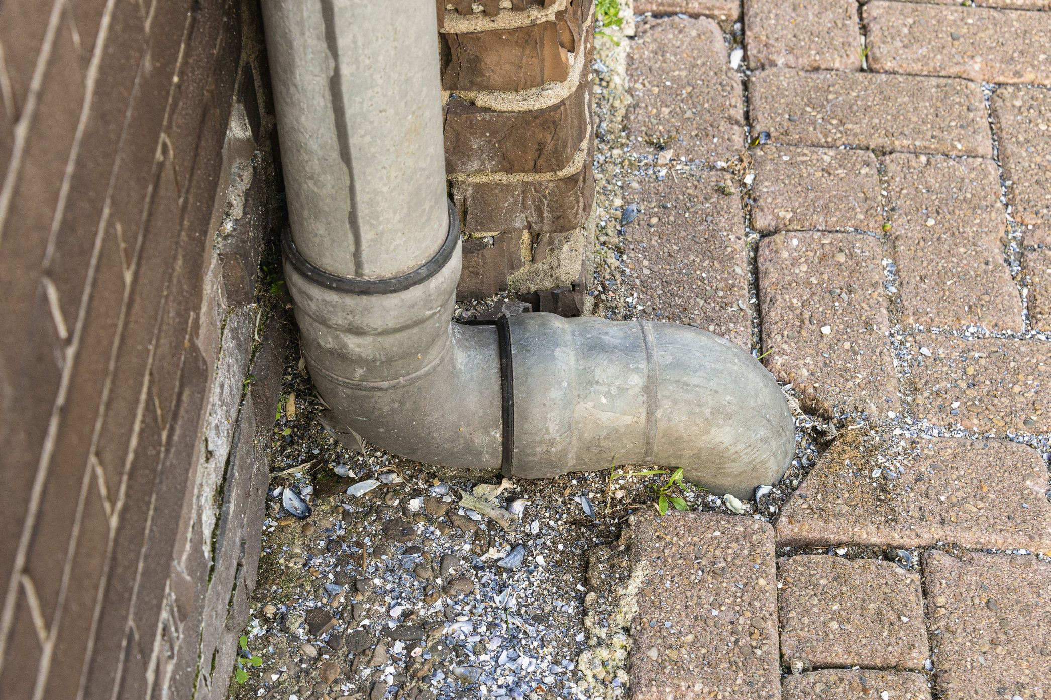 close up of down spout drain going into the ground