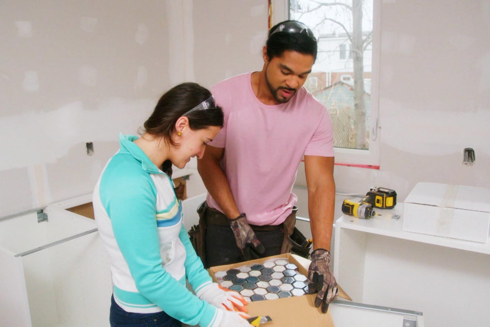 a man and woman opening box of tiles to renovate a home