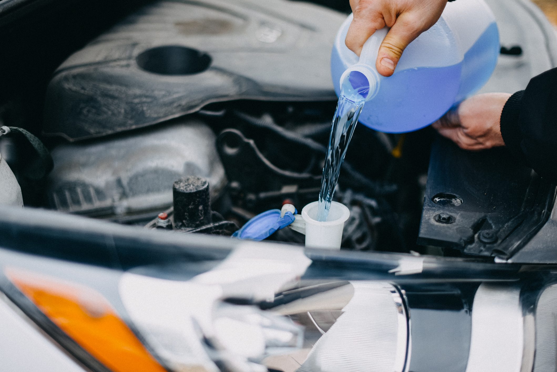 Male Hands Pouring Windshield Washer Fluid into a Car's Tank