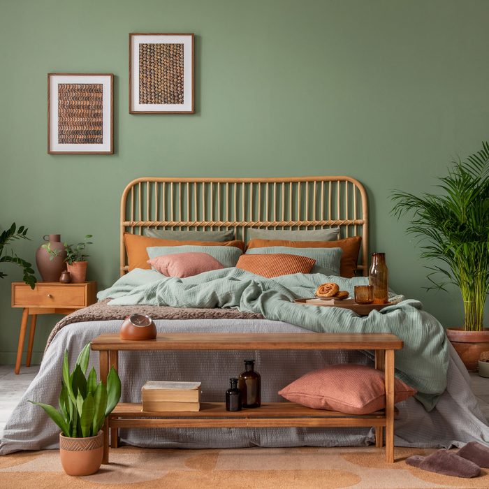 Stylish Bedroom Interior Design With Mock Up Poster Frame, Bamboo Bed, Night Table, Plants on a green background