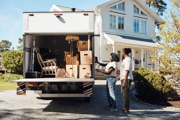 Side view of couple opening trunk of van while standing in front of house