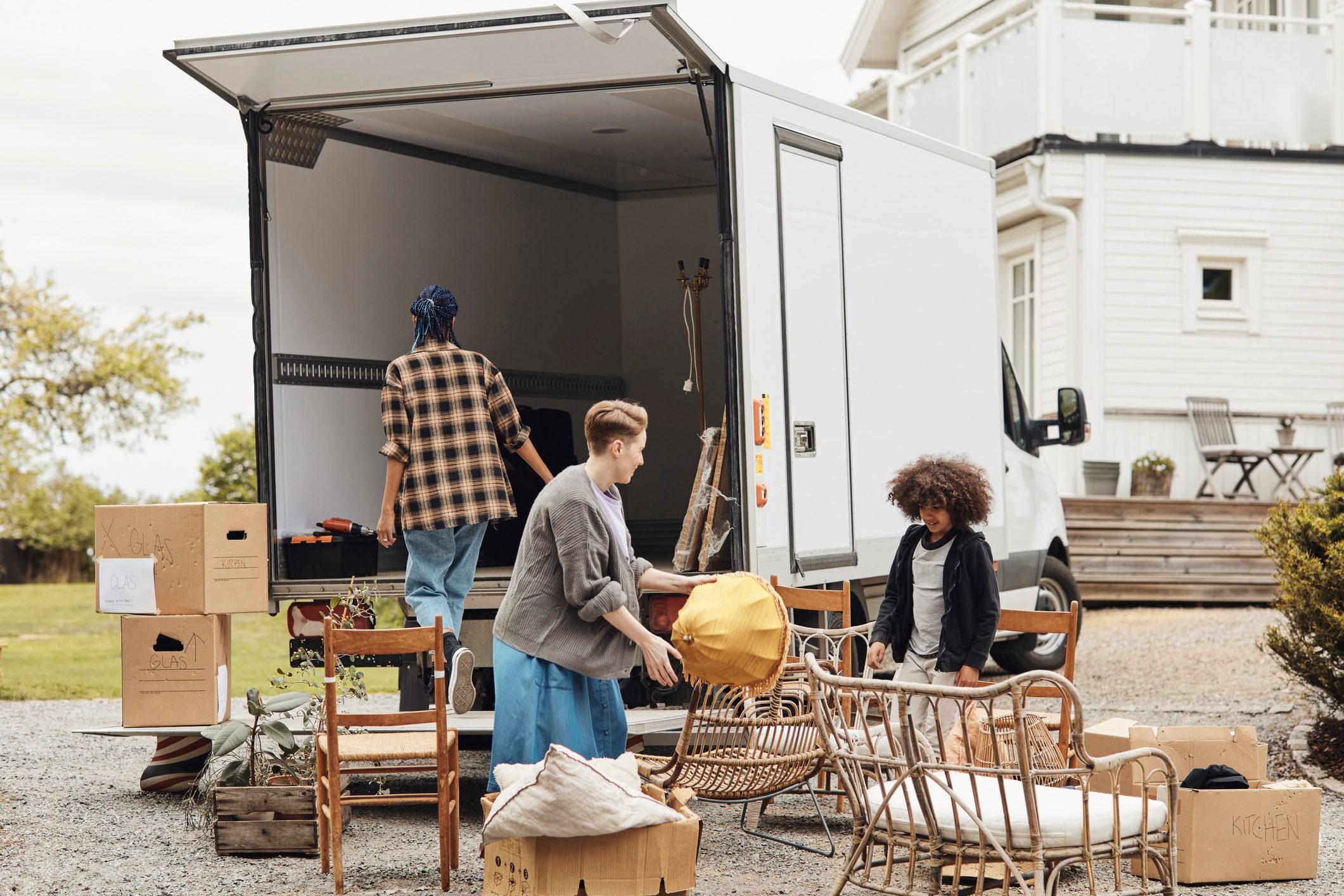 Mother holding lamp shade while arranging furniture outside van while relocating to new house