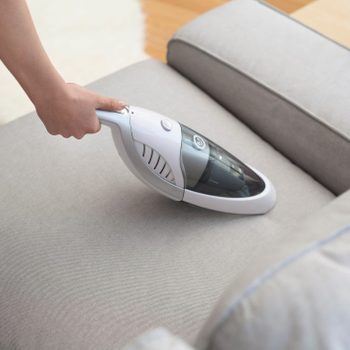 Woman With Handheld Vacuum Cleaning On Sofa 2