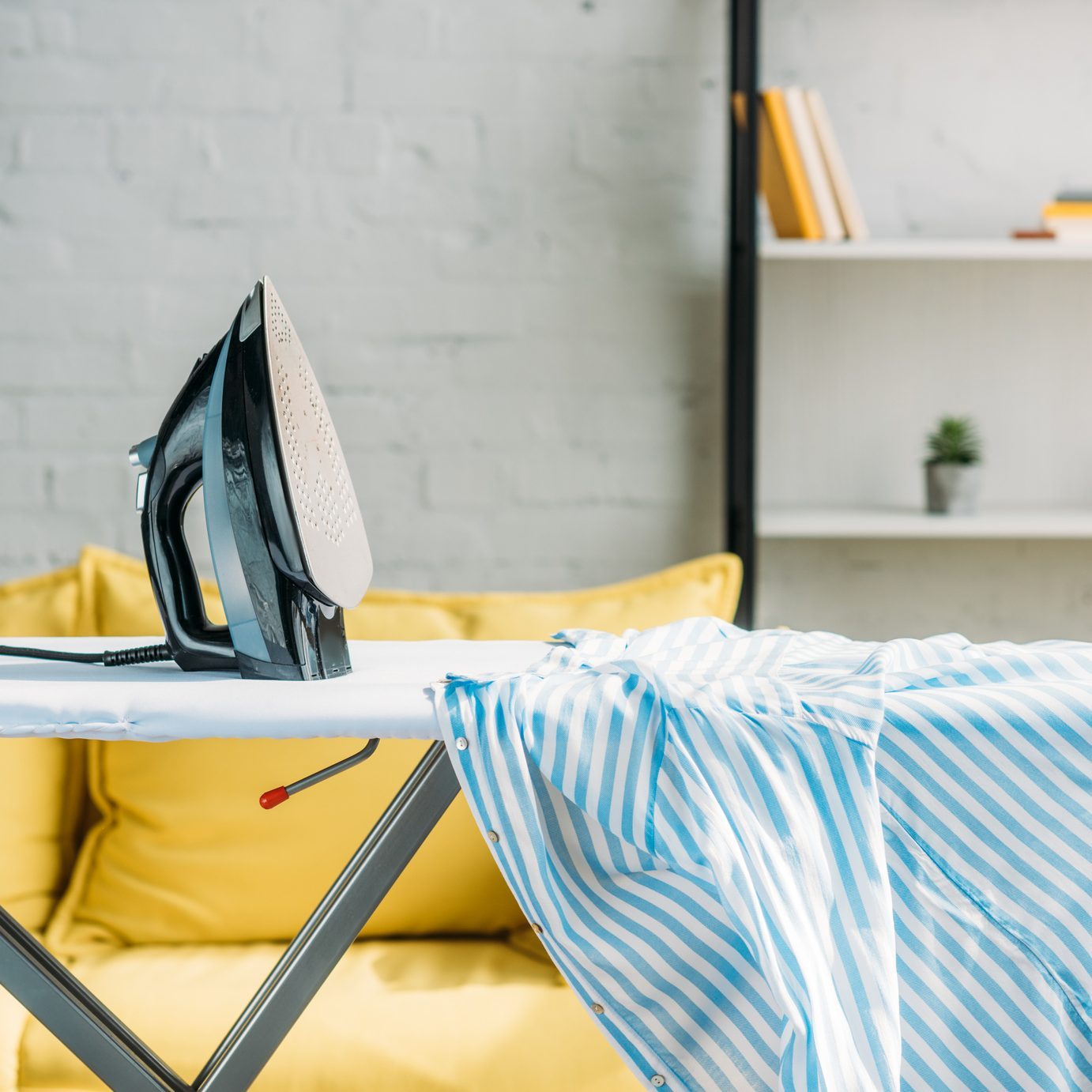 striped blue shirt and iron on ironing board at home