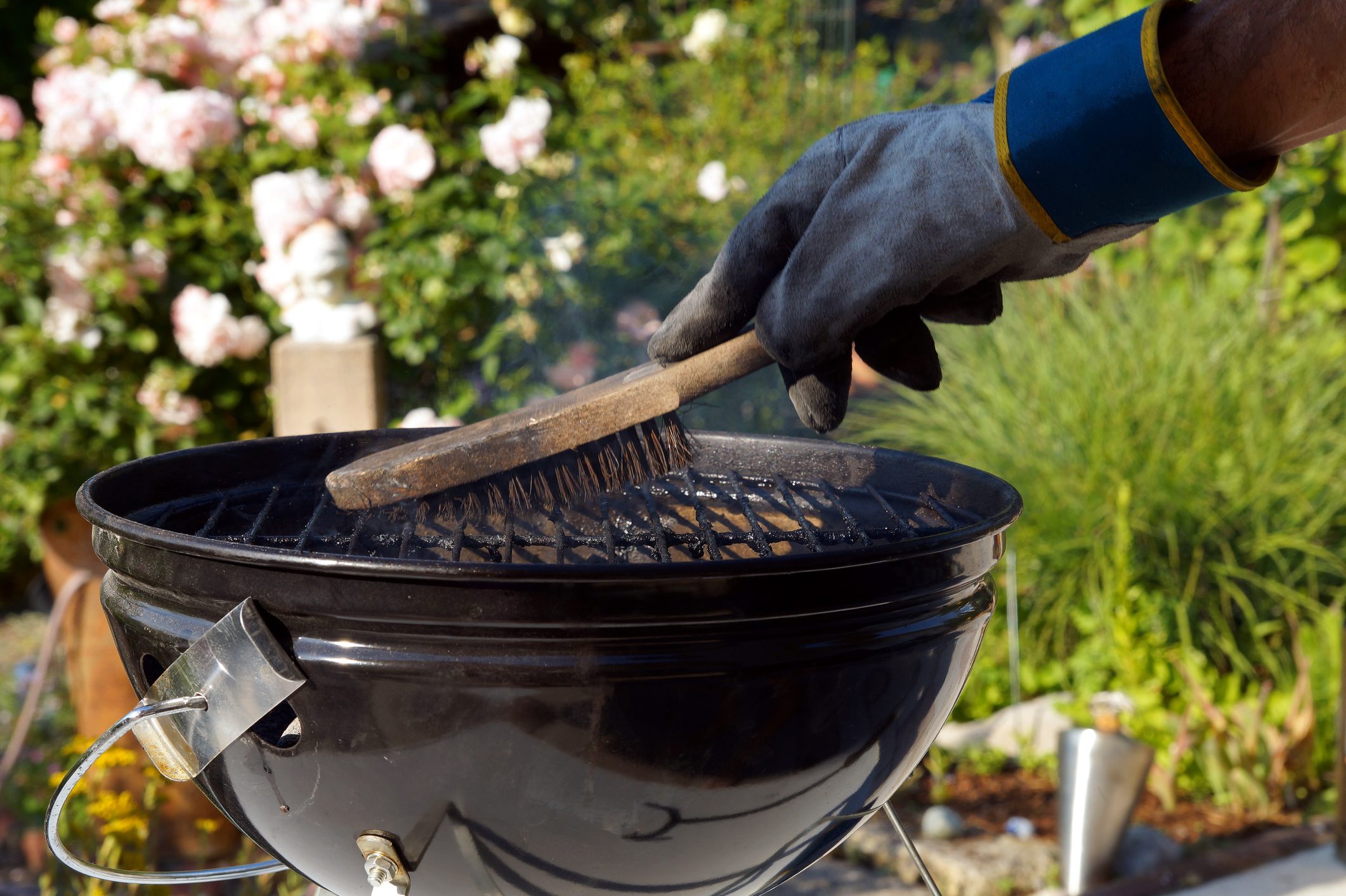 Cleaning a grill. Male hand with gloves cleans stiff brush round grill before cooking. scrubbing utensil used for cleaning a dirty grill