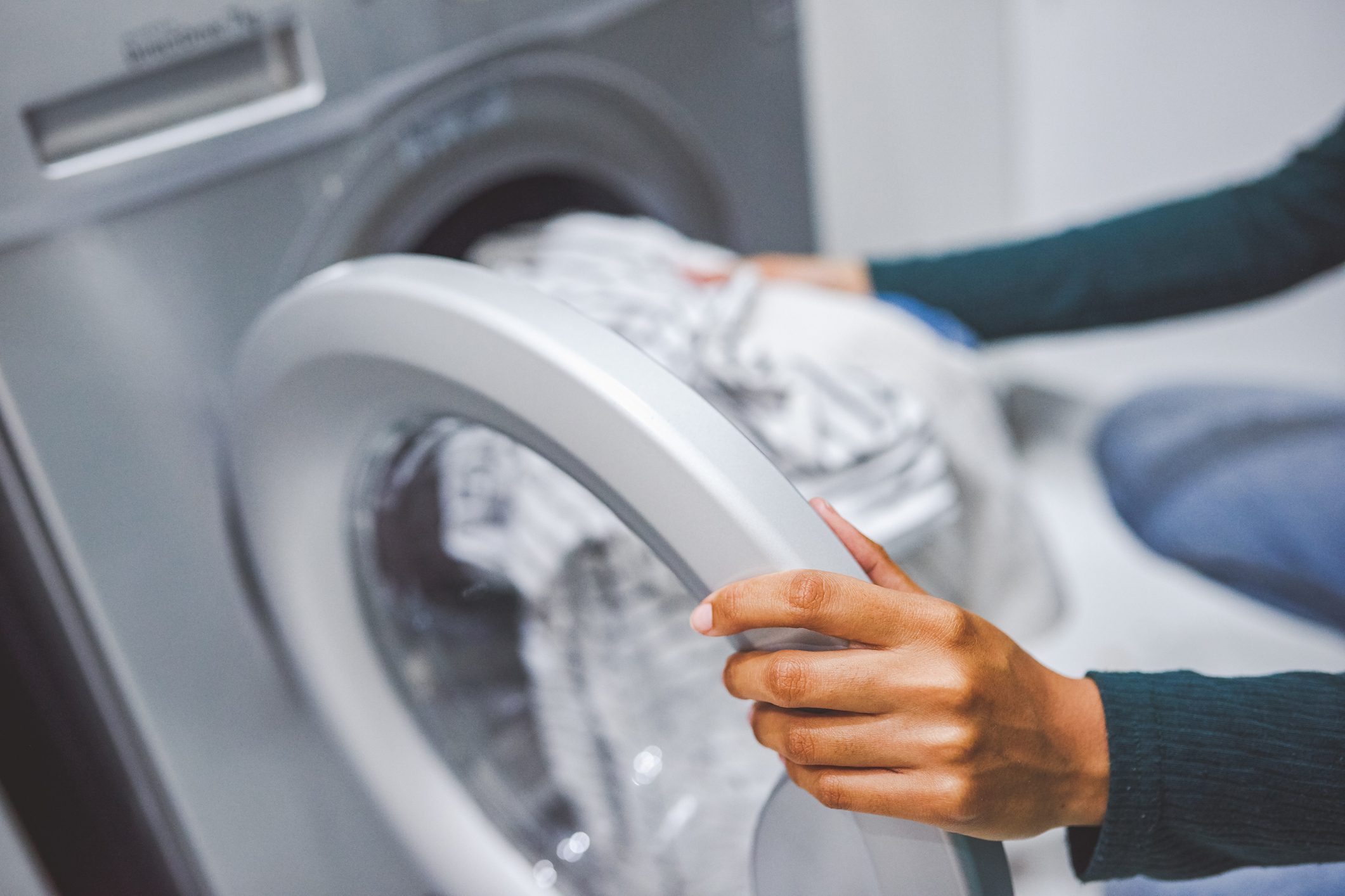 anonymous woman taking sheets out of a washing machine