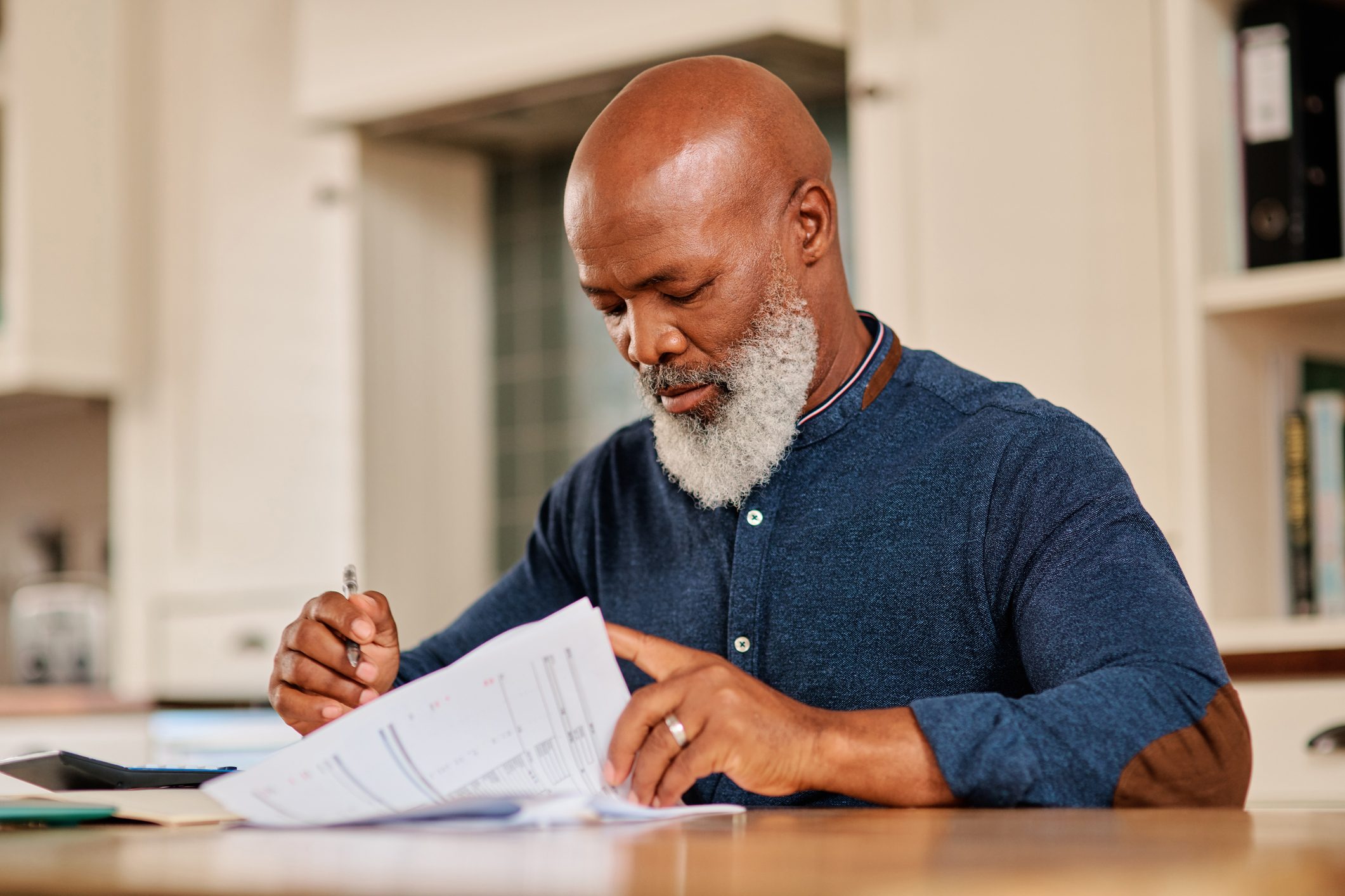 man reading over paperwork at a kitchen table