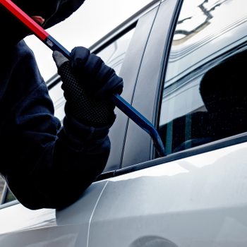 Masked burglar trying to break into a car