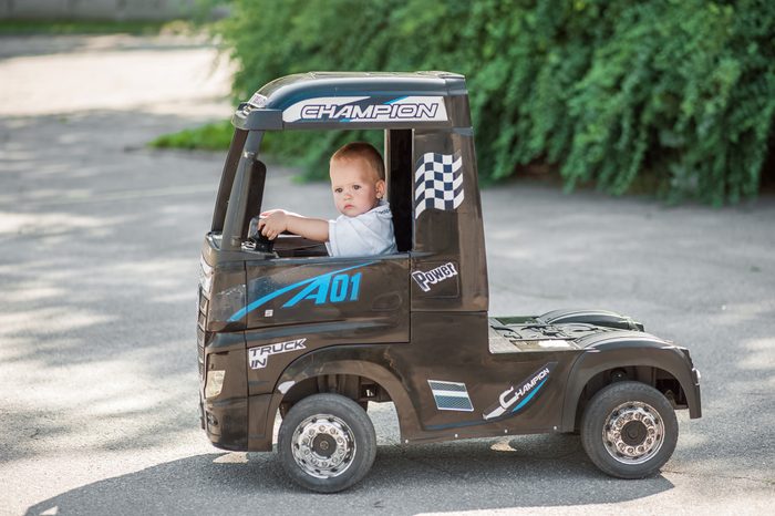 Boy toddler on large electric car close-up and copy space. Baby on truck on street...