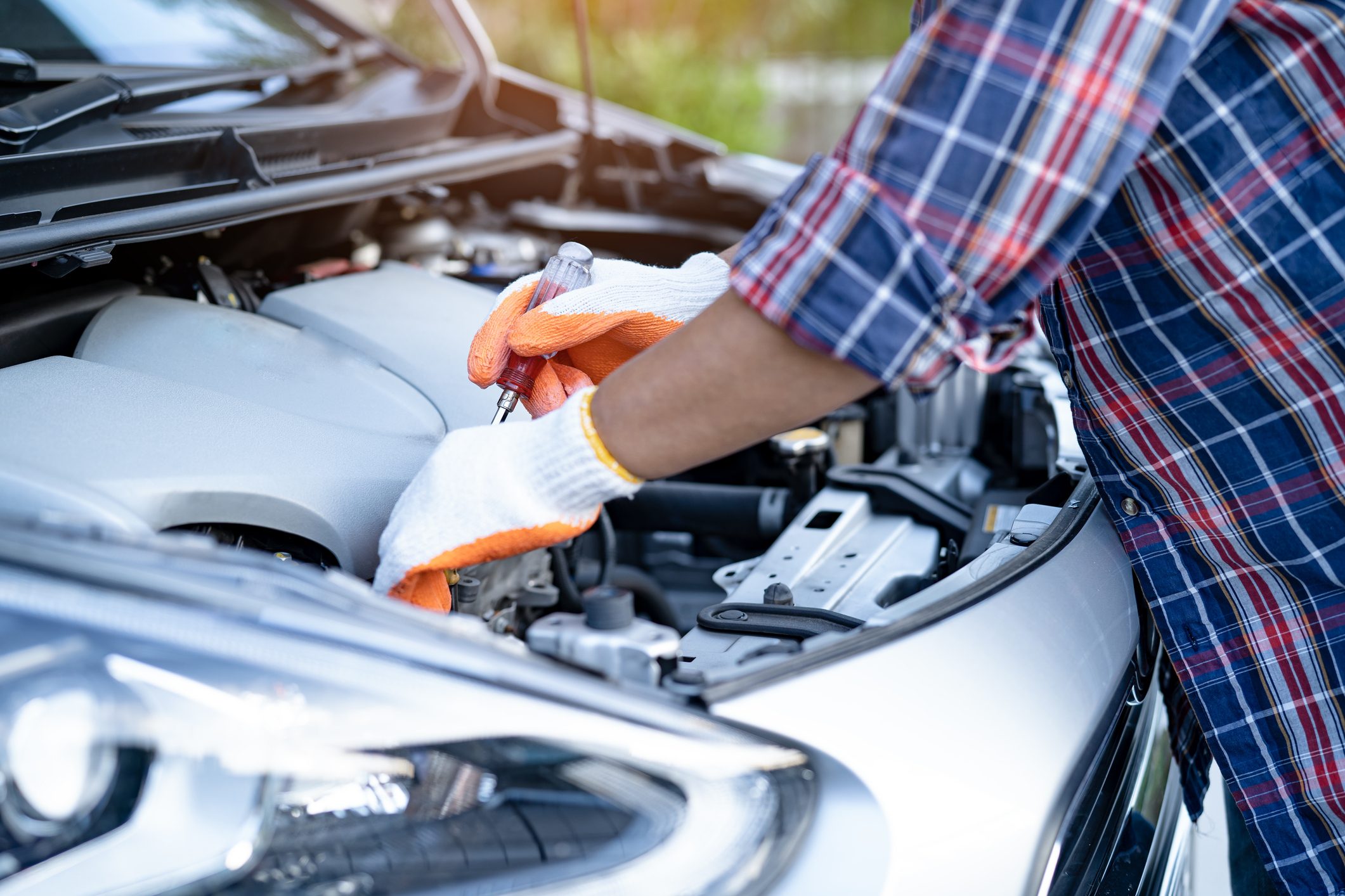 A man repairing his car by putting safety gloves on his hands