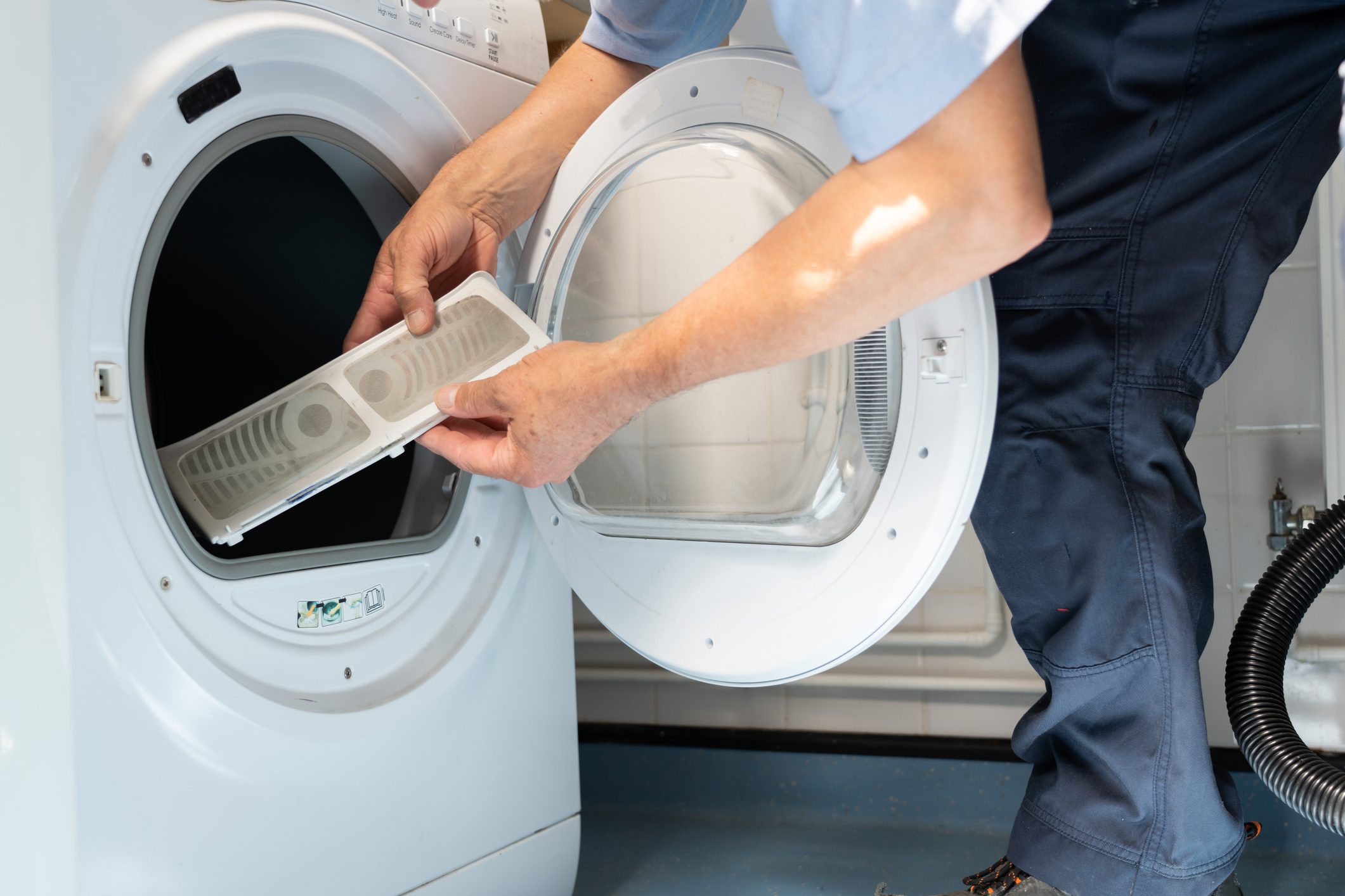 hands holding the lint filter by a dryer