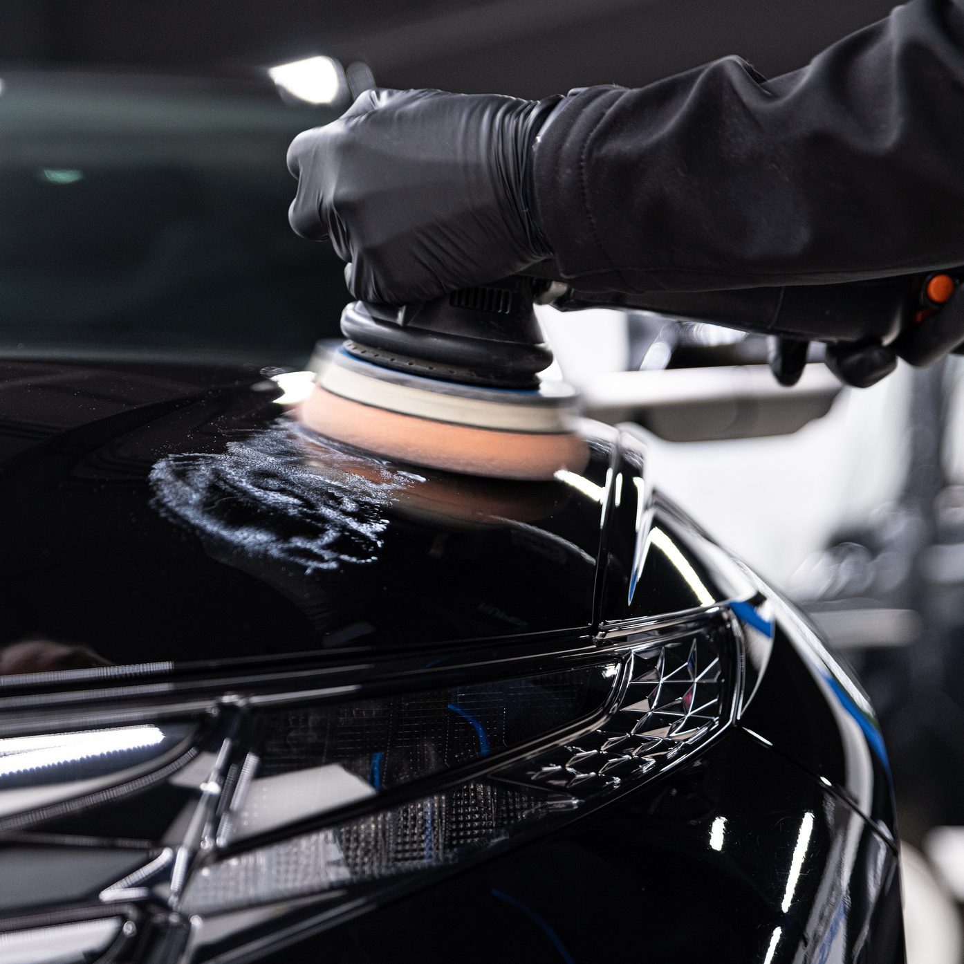 Man worker of car detailing studio removing scratches on car varnish