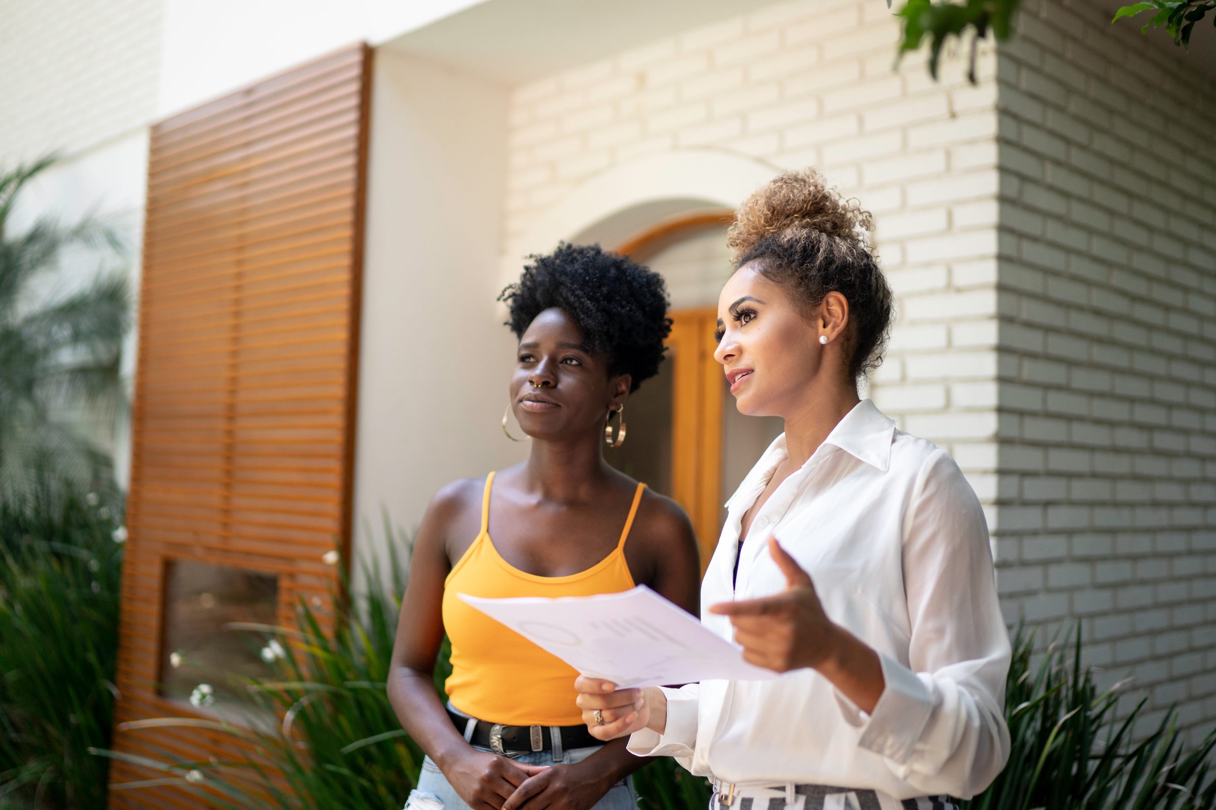 Real estate agent/financial advisor talking to a client in front of a house