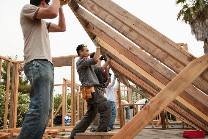 Construction workers lifting house frame