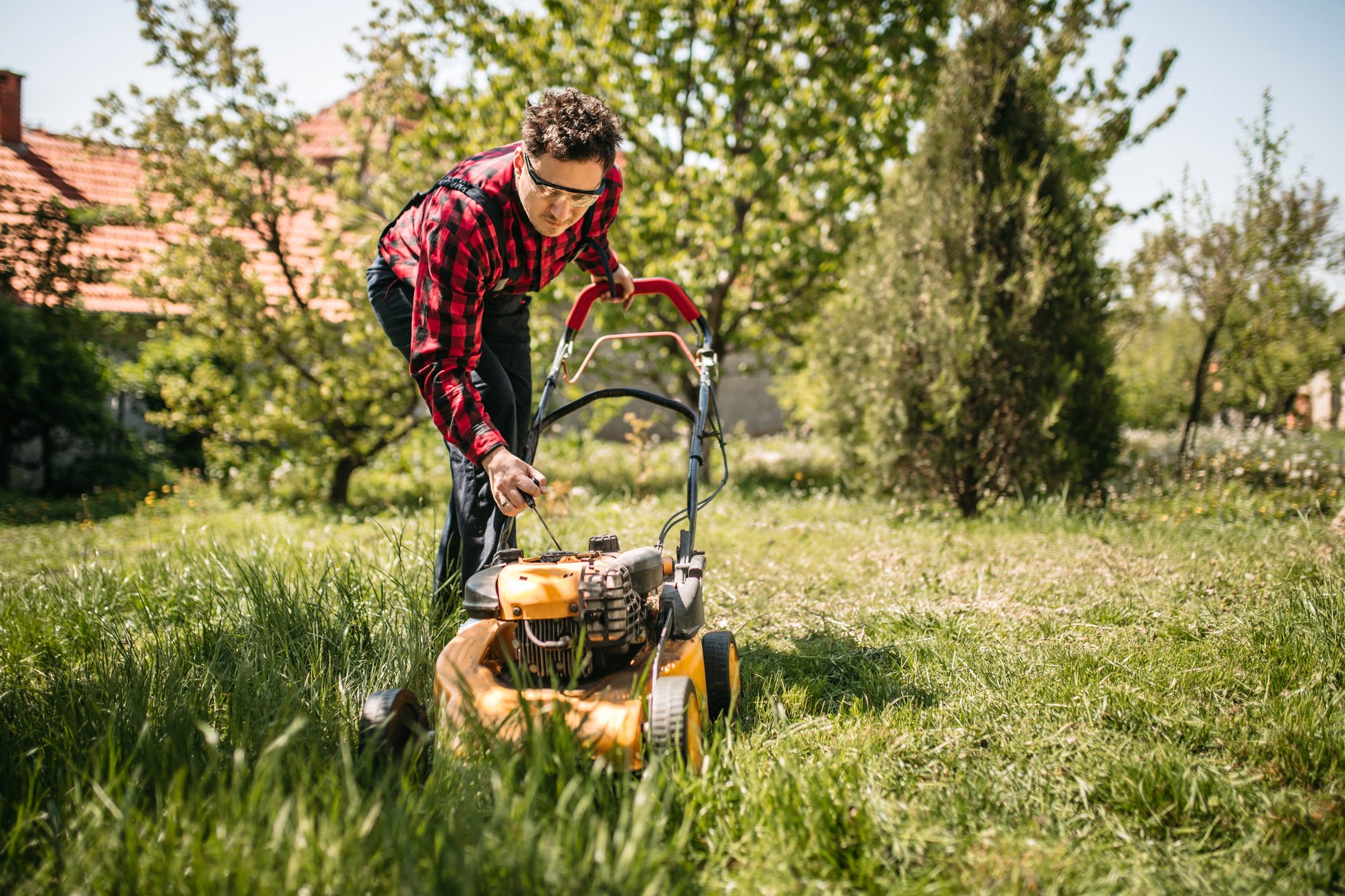 Man using a lawn mower in his back yard
