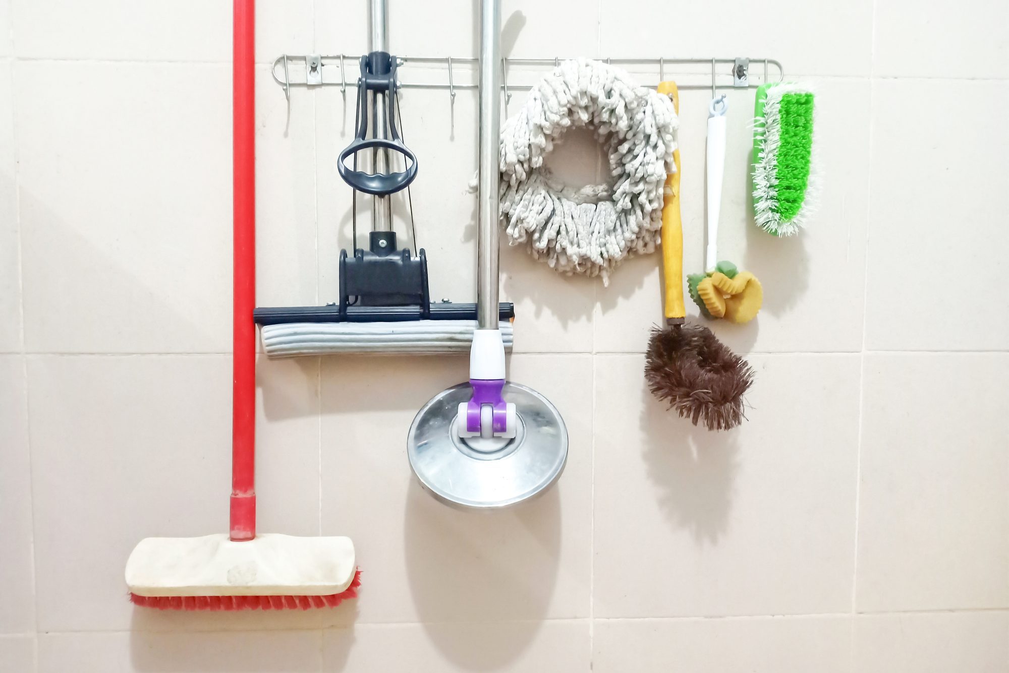 Cleaning equipment hanging on the dirty ceramic restroom wall.