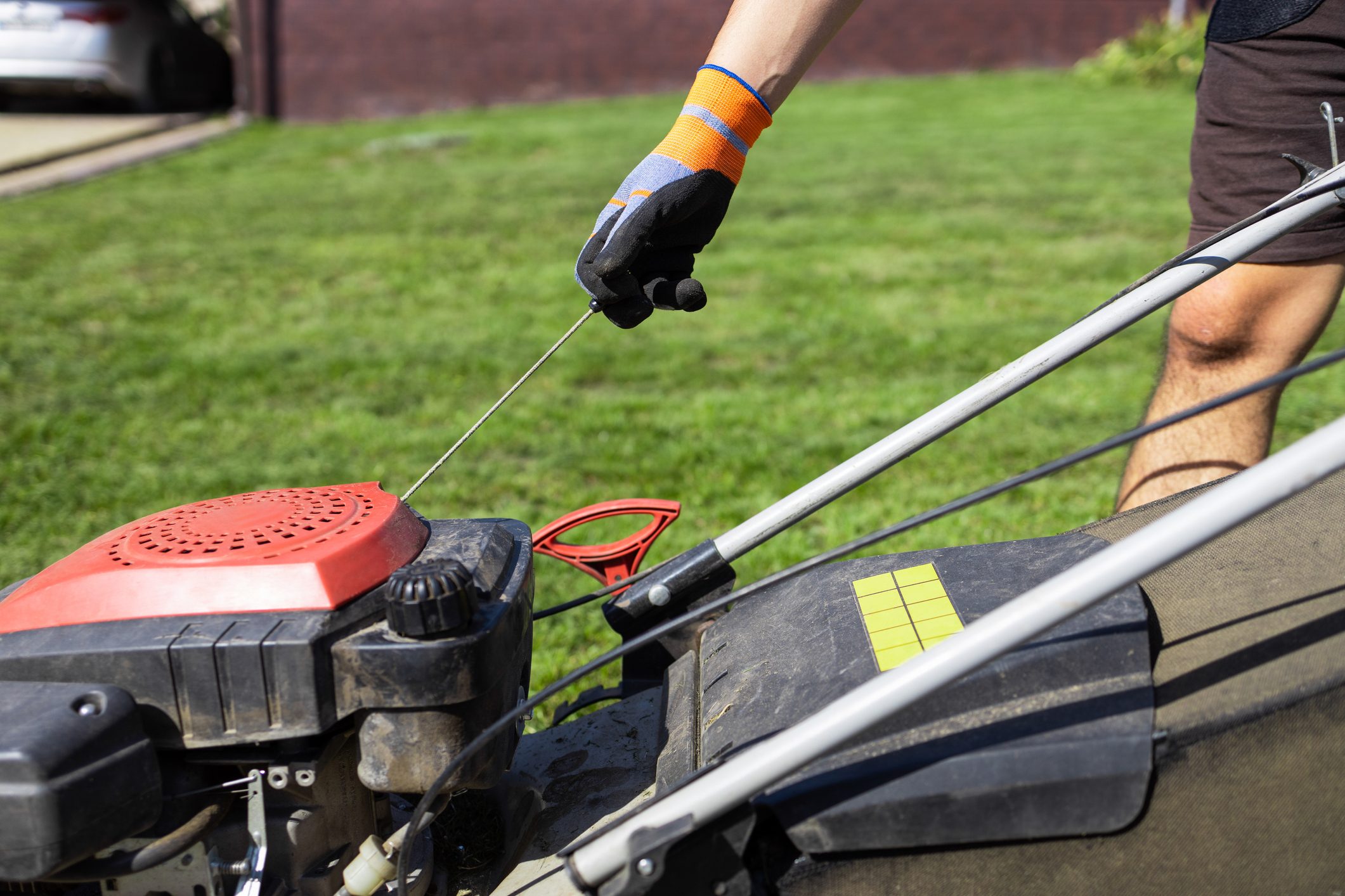 Man starts the engine of a gasoline lawn mower