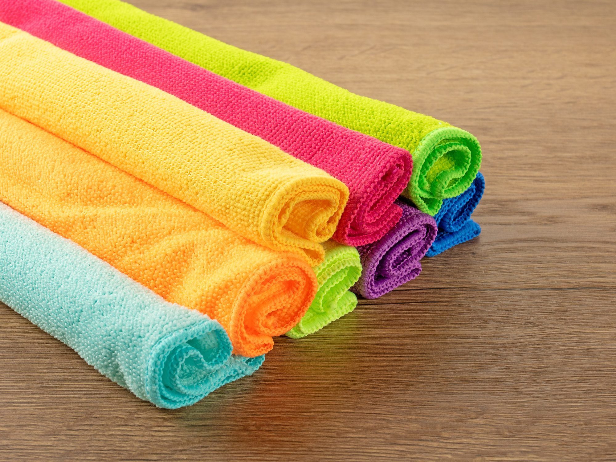 Stack Of Kitchen Microfiber Towels In Bright Colors On A Brown Wooden Table