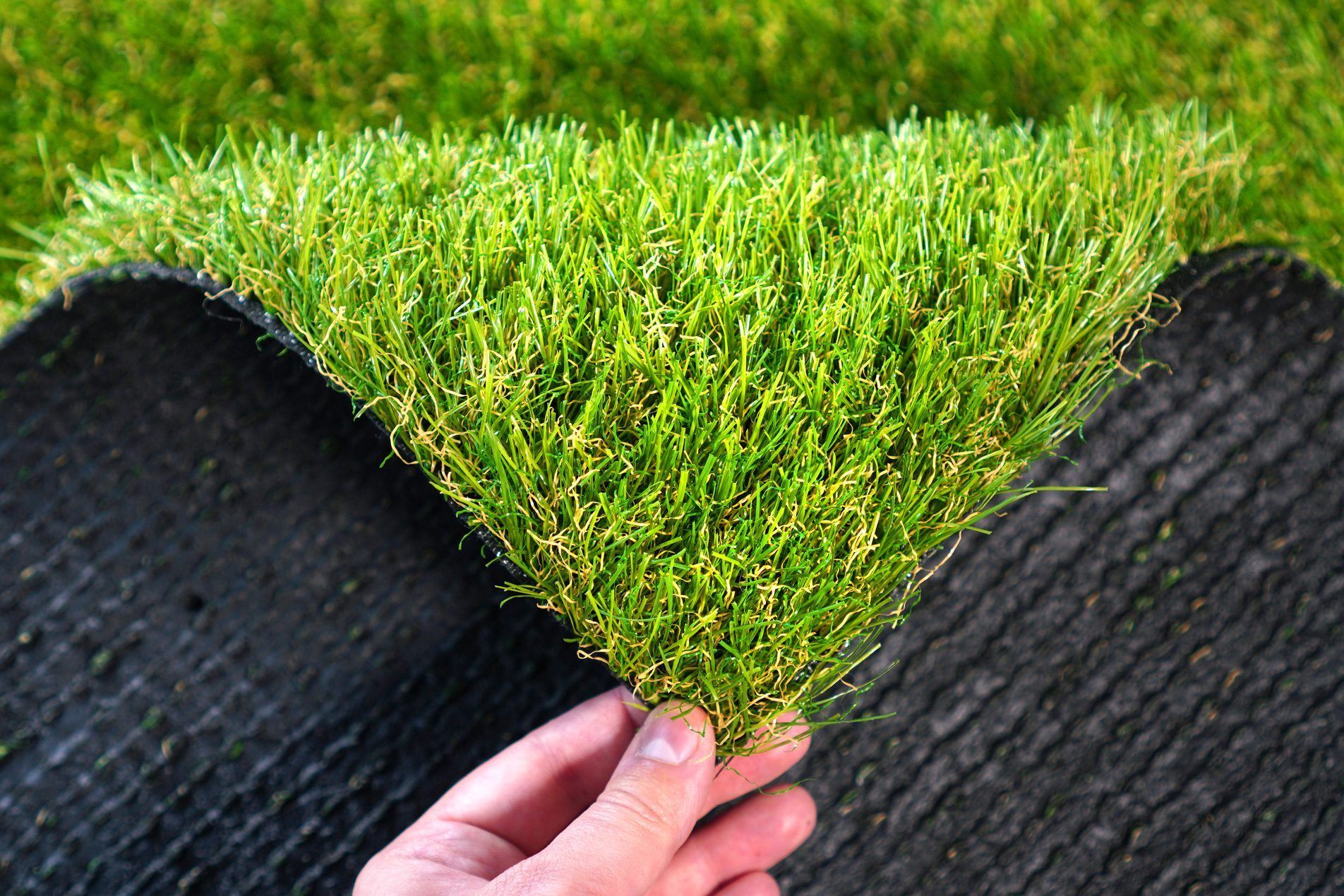Hand holding an artificial grass roll. Greenering with an artificial turf.