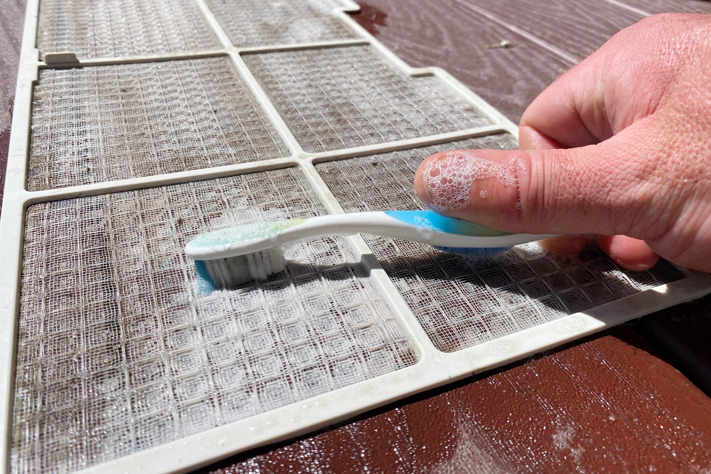 washing an air conditioner filter with a tooth brush