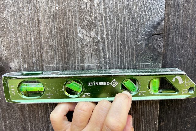 using a level on the fence before cutting the hole