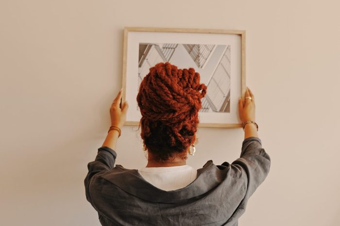 Shot of a unrecognizable female hanging a painting at home