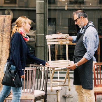 Costumer and owner discussing over chair outside shop