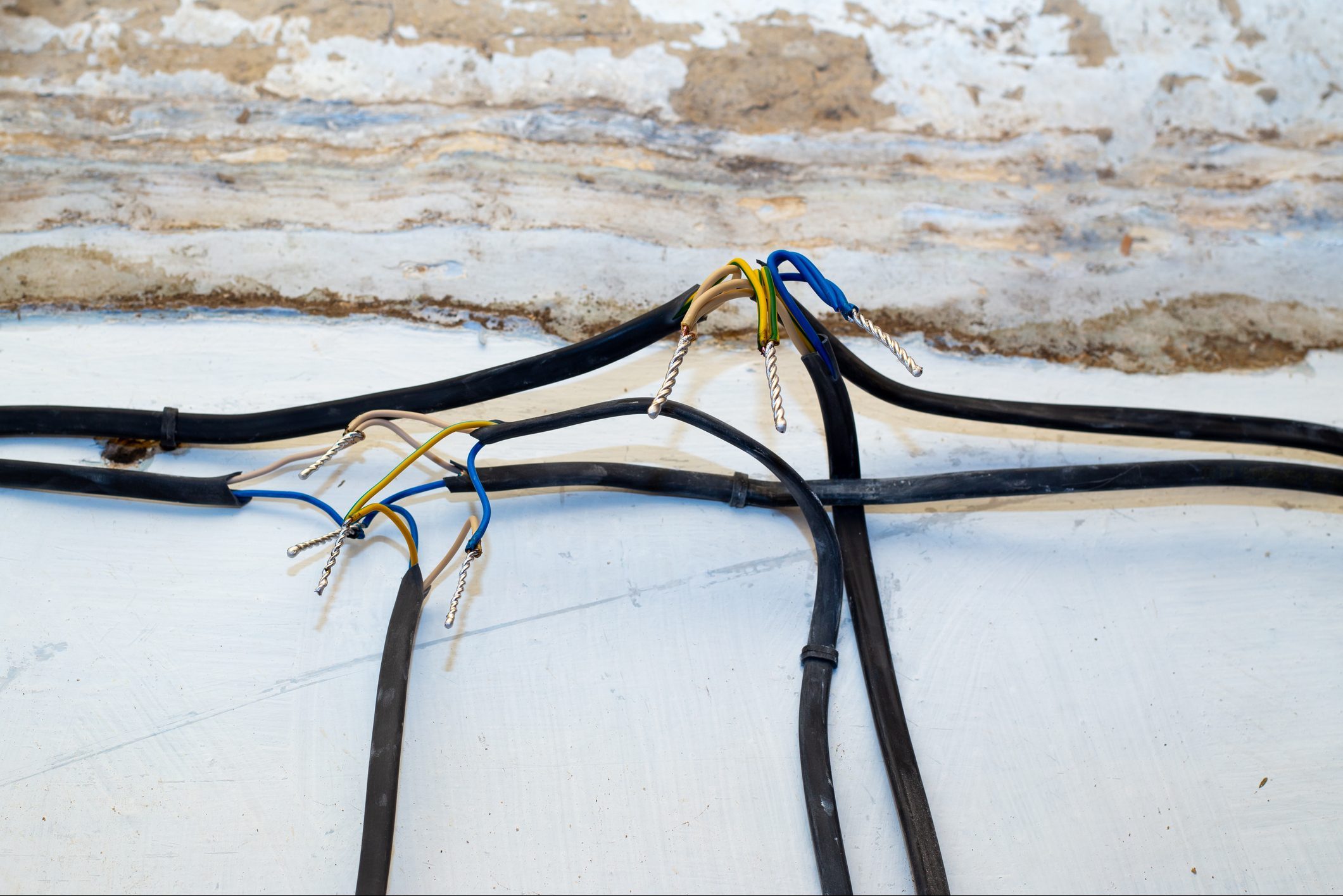 Connection of wires against the background of a wall in a house under construction. Twisting, soldering, welding of electrical cables