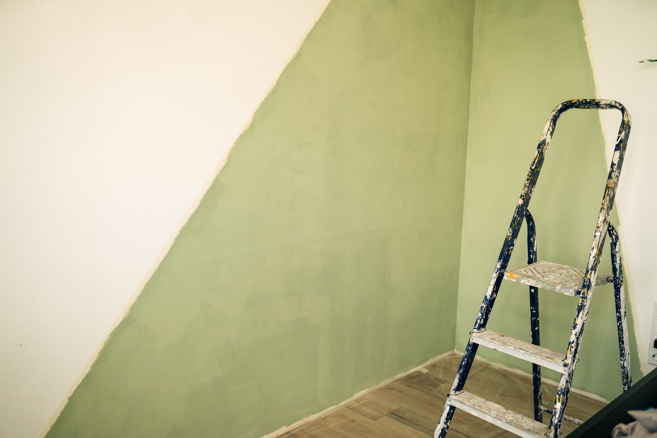 Paintbrush on can on top of step ladder with painted wall