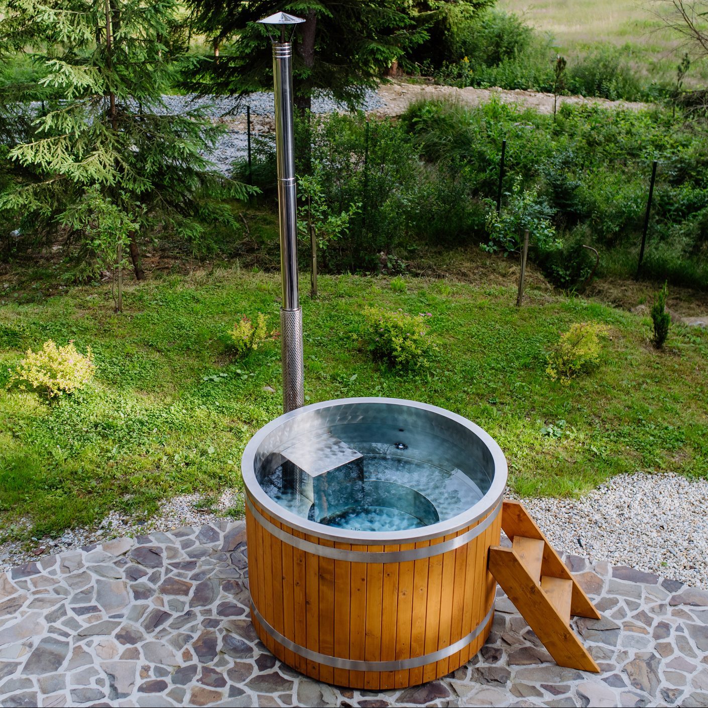 Wooden hottub with a fireplace to burn wood and heat water in backyard in mountains.