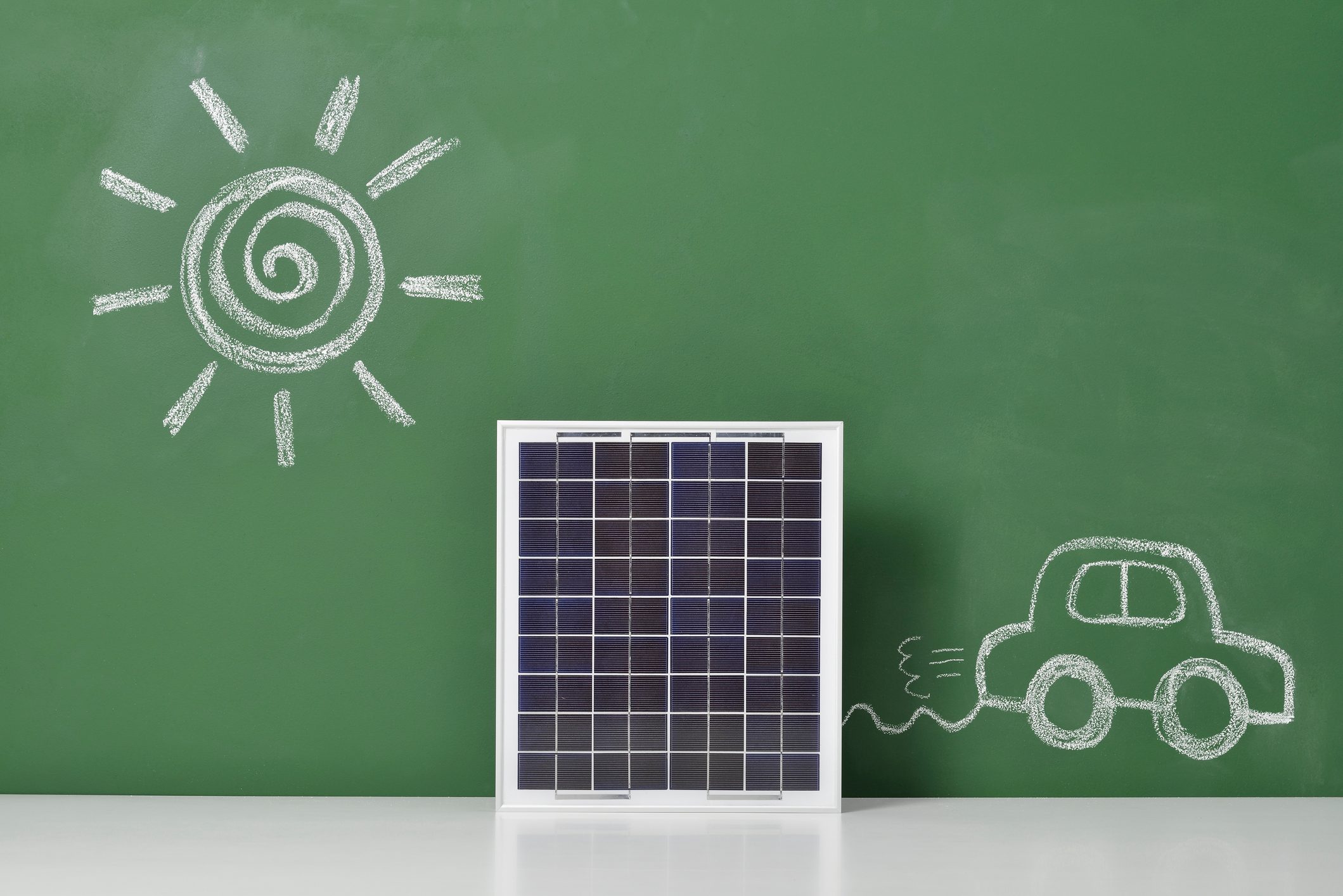 Electric car powered by solar panel on chalkboard