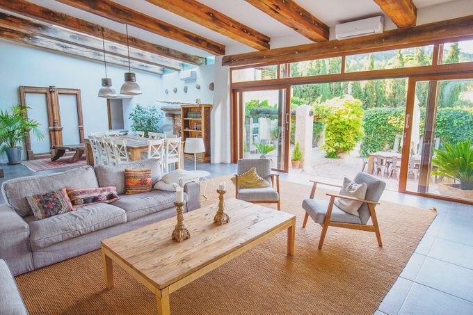 Elegant farmhouse living area with sofas and easy chairs and patio doors open on to garden