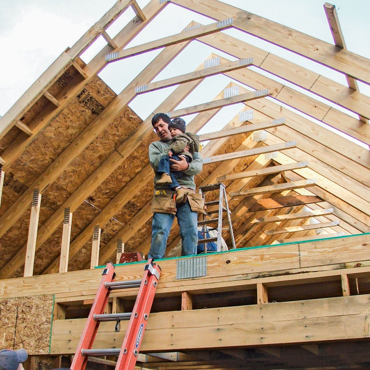 A Man Standing on Garage Attic Trusses While Holding a Child in hands