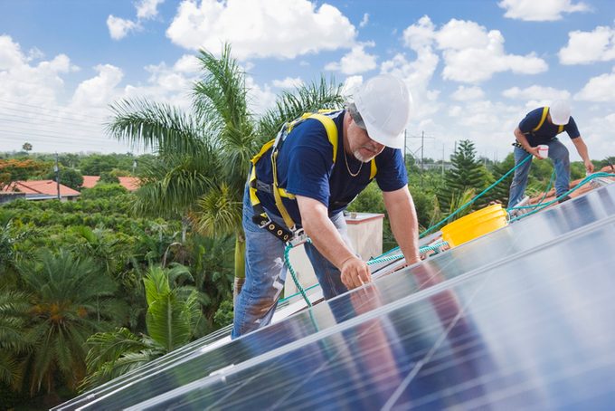 Two men installing solar panels on residential home roof