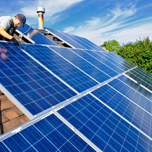 Man installing alternative energy photovoltaic solar panels on roof