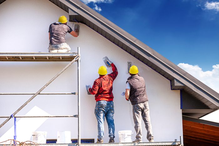 Construction workers plasters the building facade.